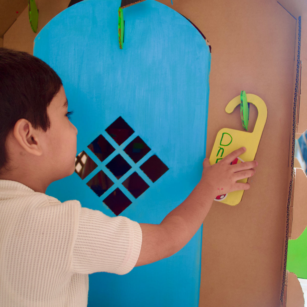 Boy placing a door hanger on his DUDUK Cubby House