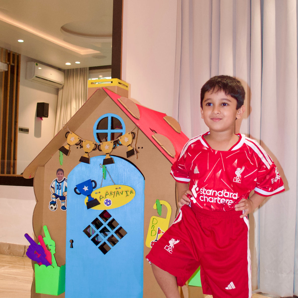 Boy in a football kit with a ball beside his DUDUK Cubby House