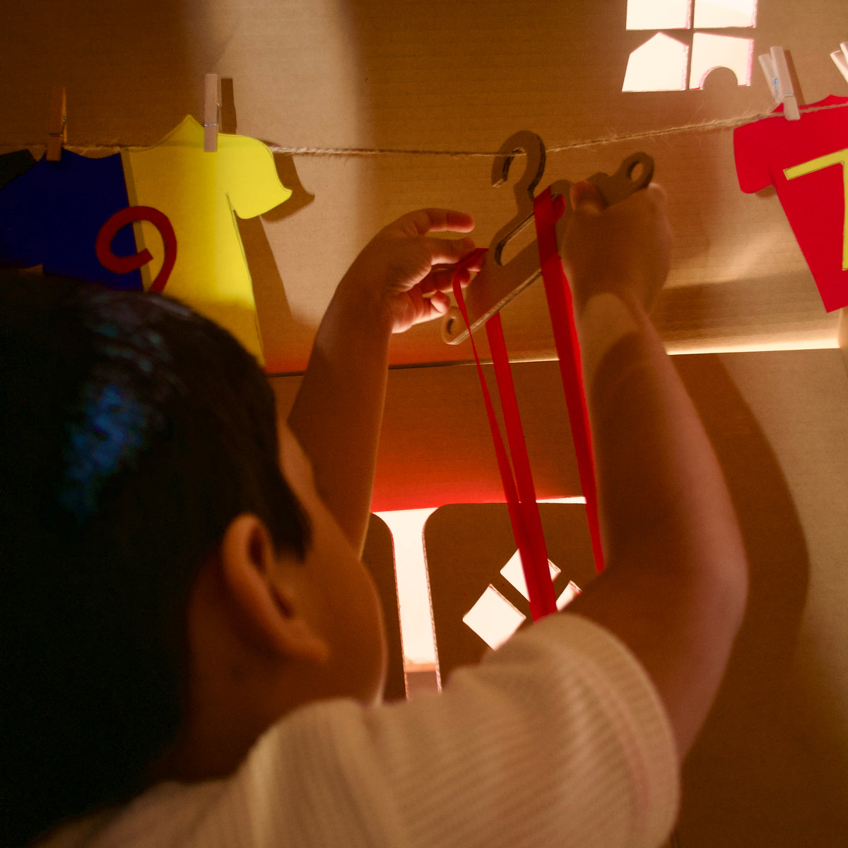 Boy pegging a medal on a line in his football-themed DUDUK Cubby House