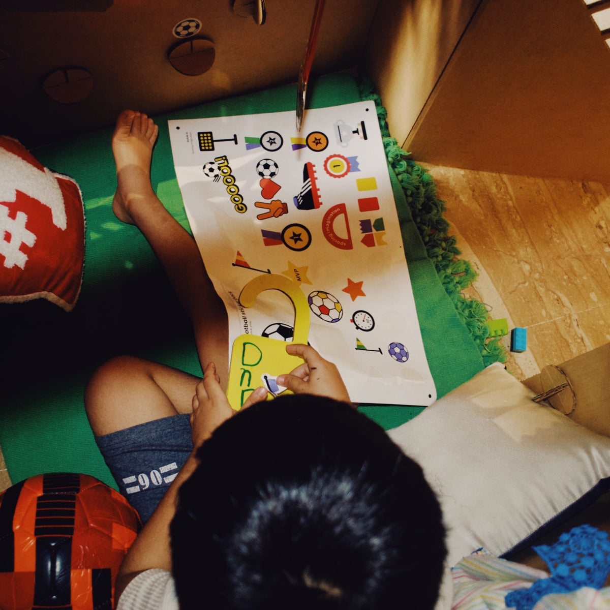 Overhead view of children playing with football stickers on a DUDUK cubby house