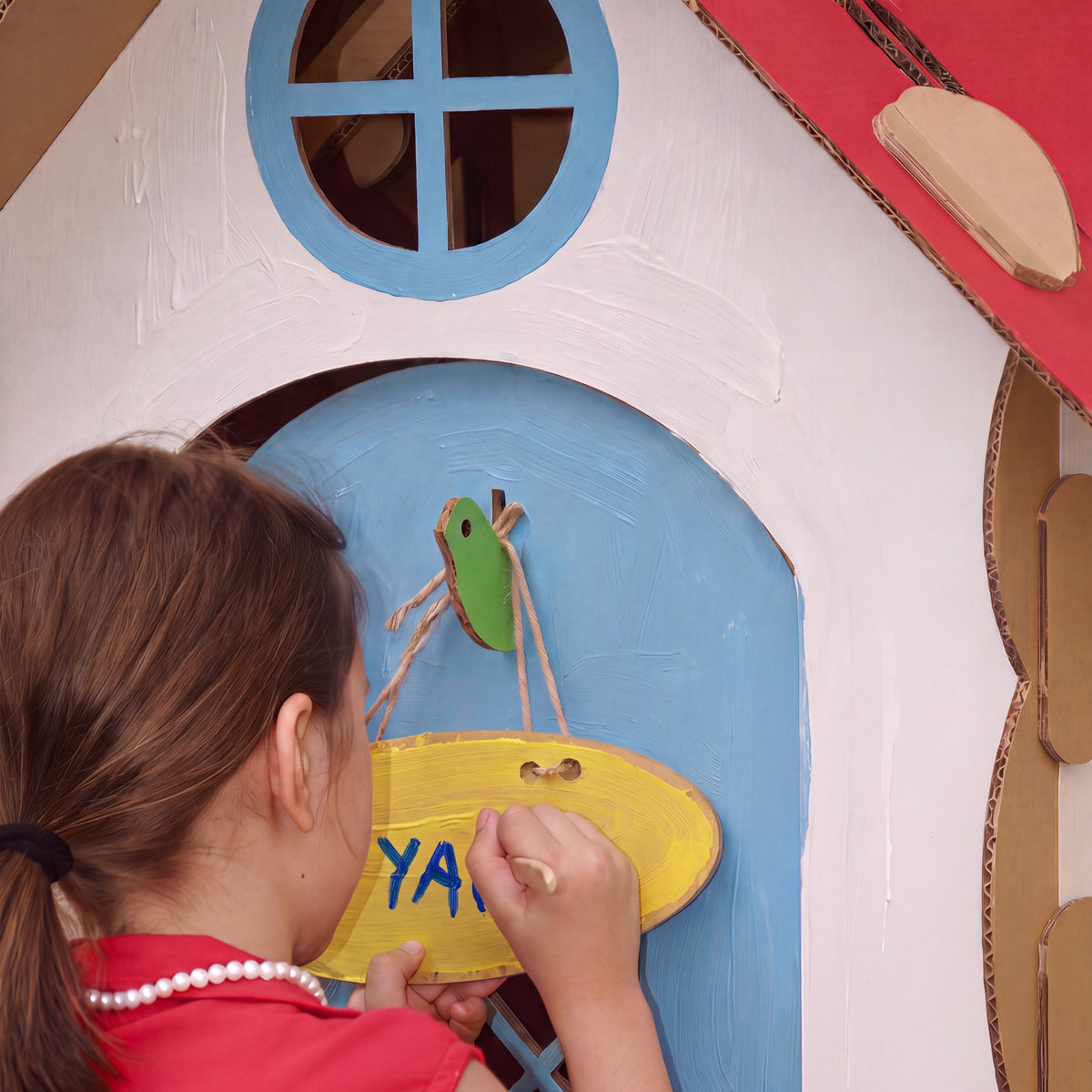 Girl painting the nameplate on the door of her DUDUK Cubby House