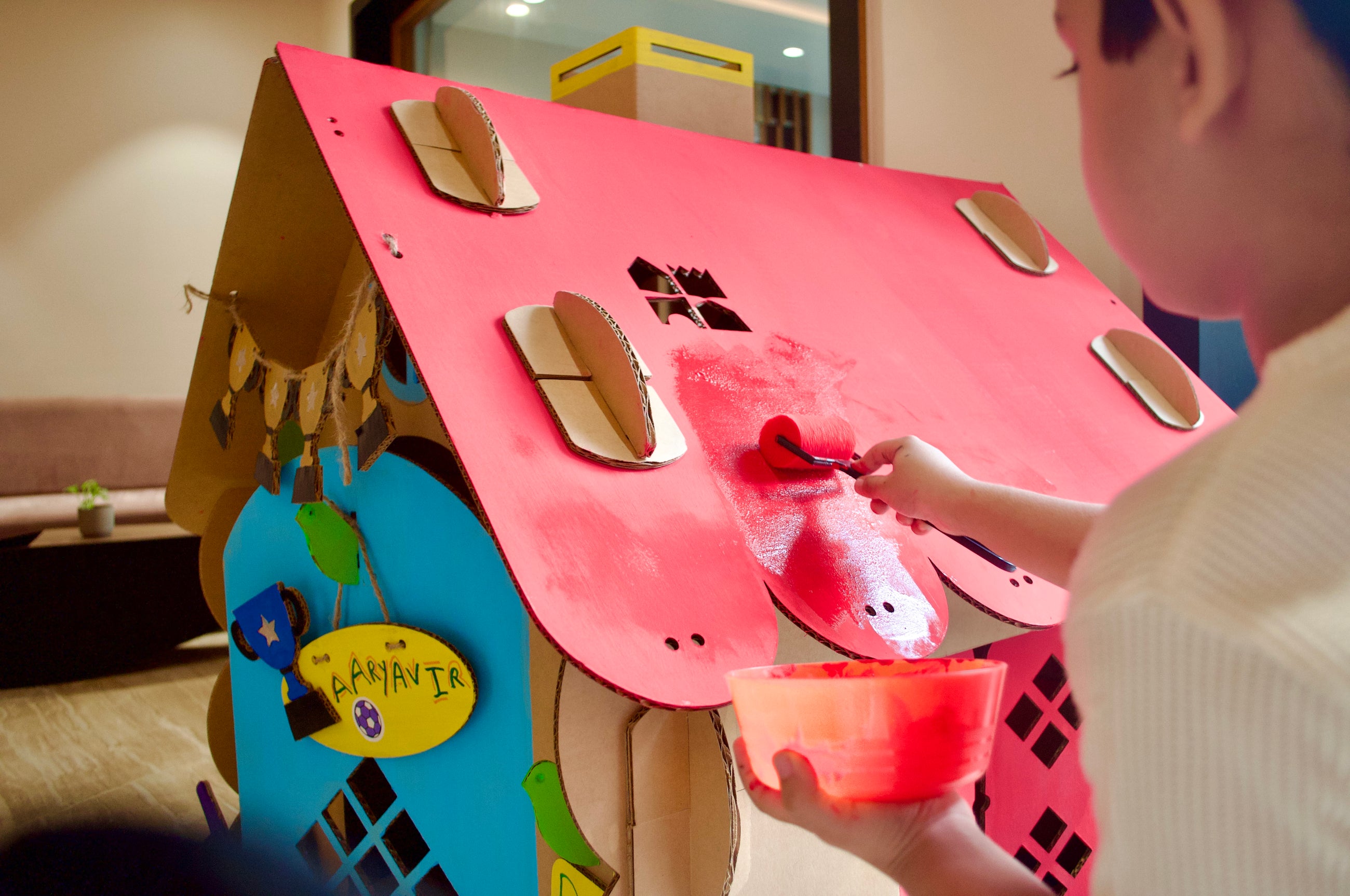 A child painting a DUDUK playhouse