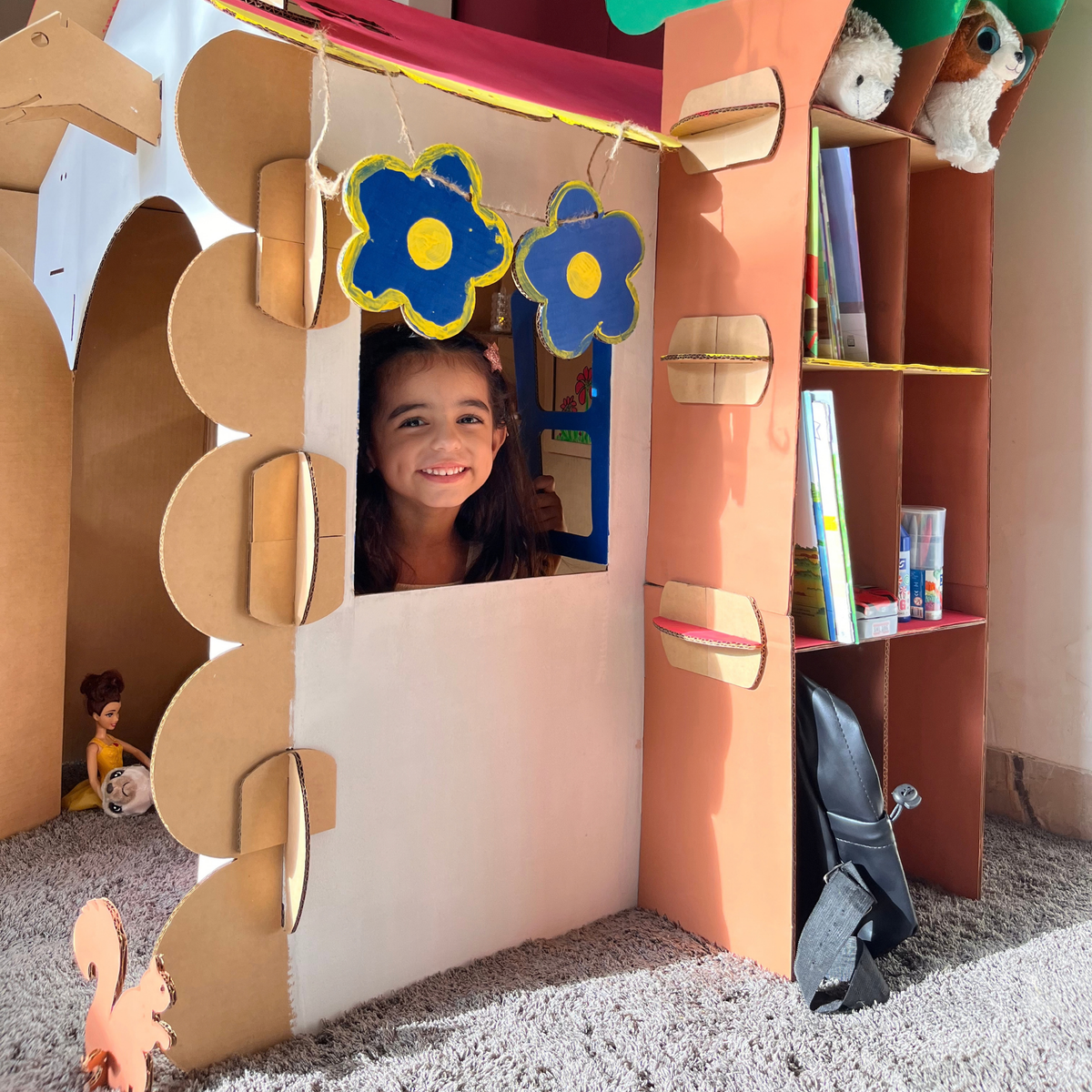 Girl at the window of a DUDUK Tree House with flowers, bunting and the trunk bookshelf