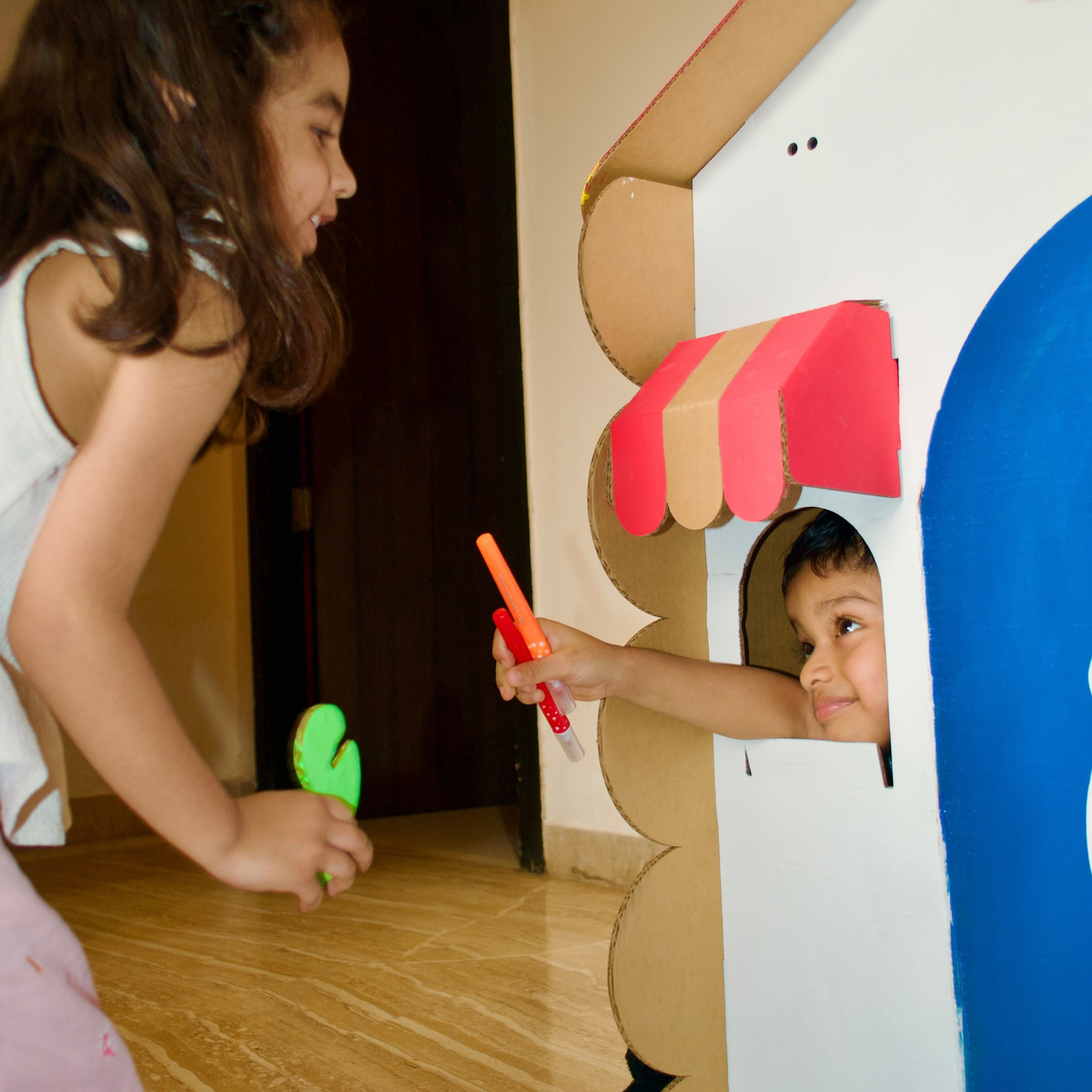Girl painting the window awning of a DUDUK Tree House while a boy peeks out